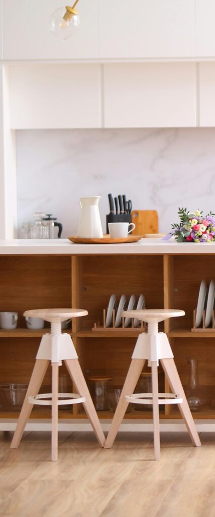 Elegant kitchen interior featuring wooden stools and organized shelves, perfect for contemporary home design.