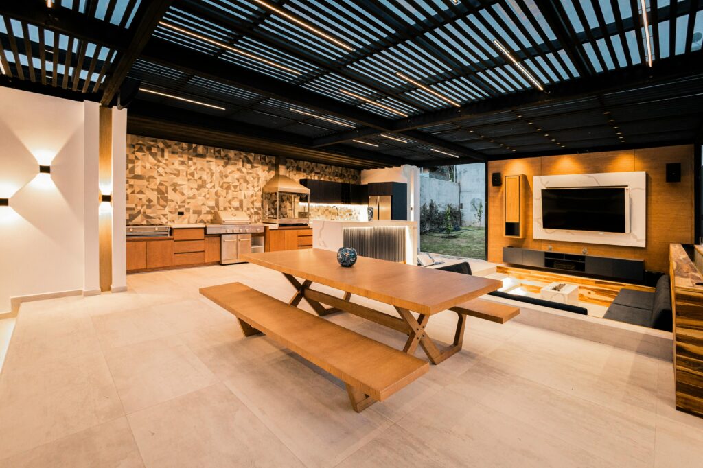 Spacious outdoor kitchen and living space featuring sleek design, wood accents, and a mounted TV.
