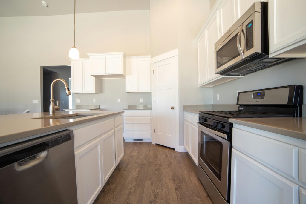 Spacious modern kitchen with white cabinets and stainless steel appliances.